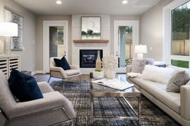 Bright living room with white sofas, blue accents, fireplace, and large windows