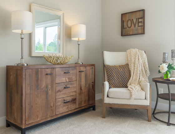 Cozy living room corner with rustic cabinet, armchair, side table, lamps, and “LOVE” wall art.