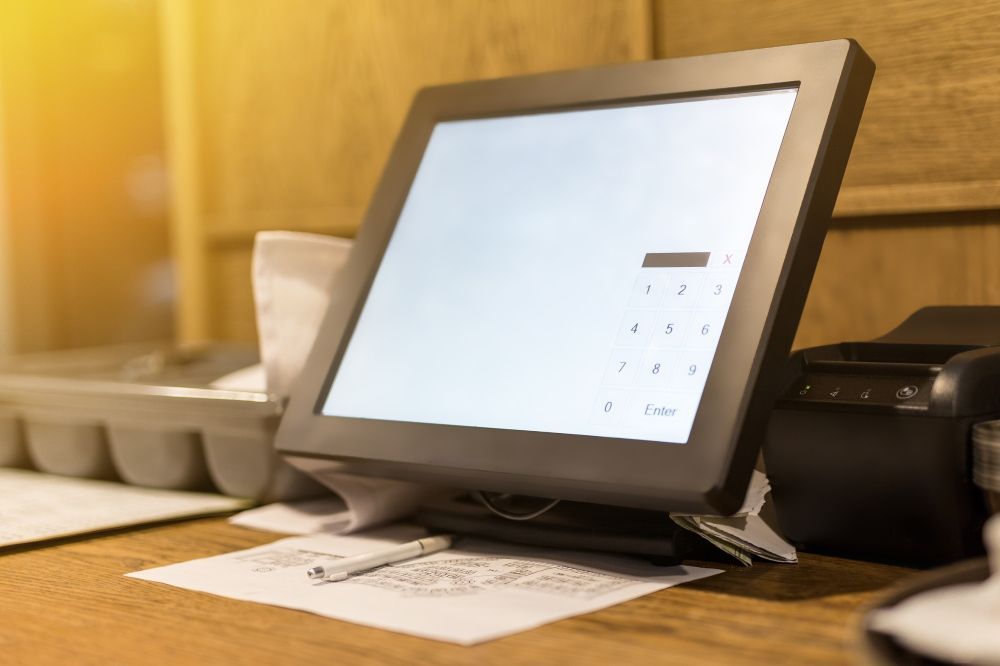 A Computer Monitor Is Sitting On A Wooden Desk Next To A Printer — Coastal Registers & POS In Ruthven, NSW