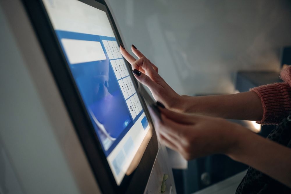 A Woman Is Using A Touchscreen Computer In A Restaurant — Coastal Registers & POS In Ruthven, NSW