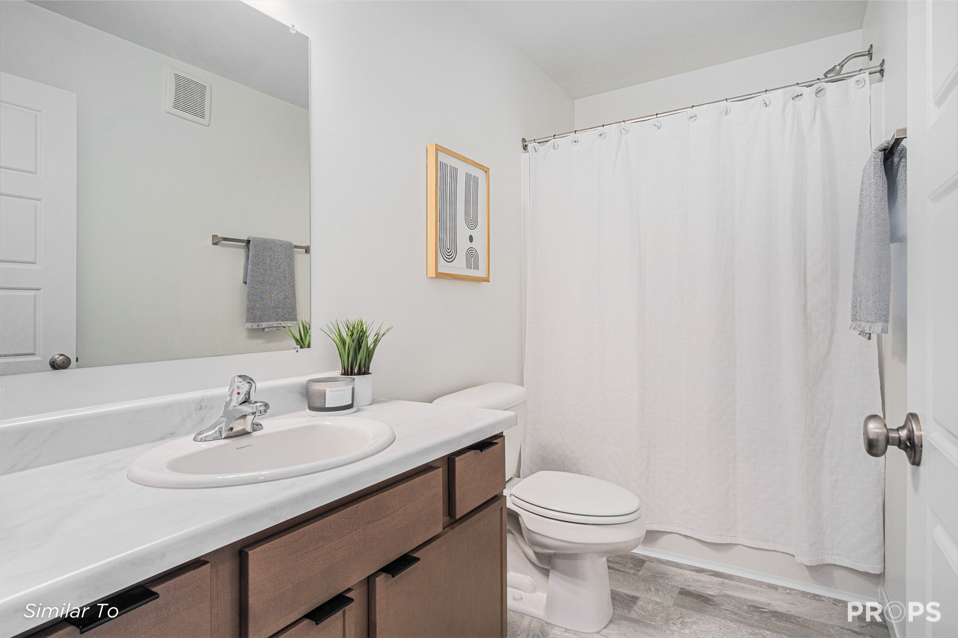 Bright bathroom with double sink vanity, toilet, shower curtain, and large wall mirror