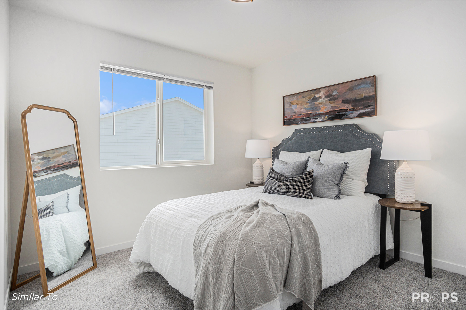 Bright bedroom with a bed, floor mirror, window, and bedside lamps
