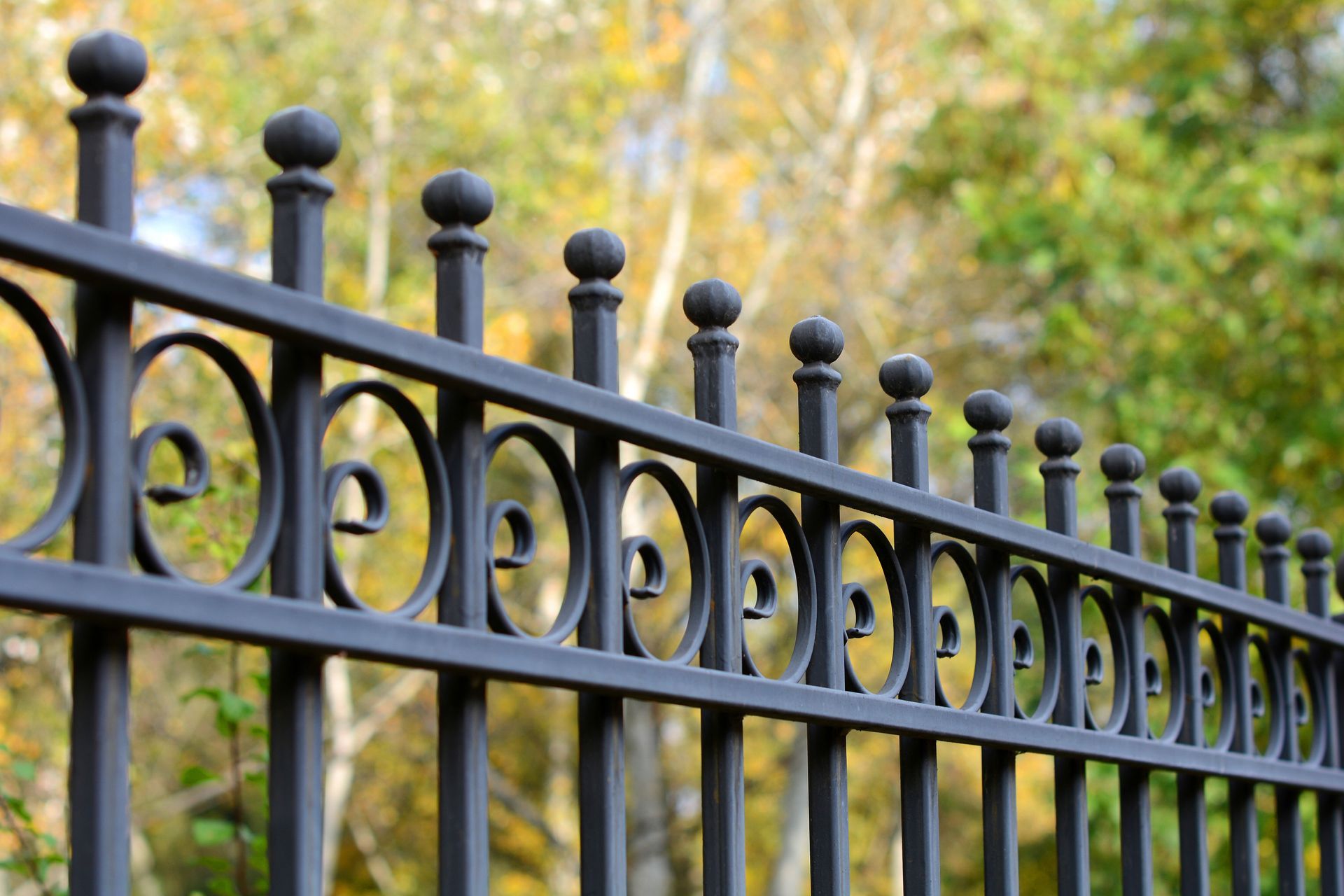 A black fence with a sliding gate in front of a house.