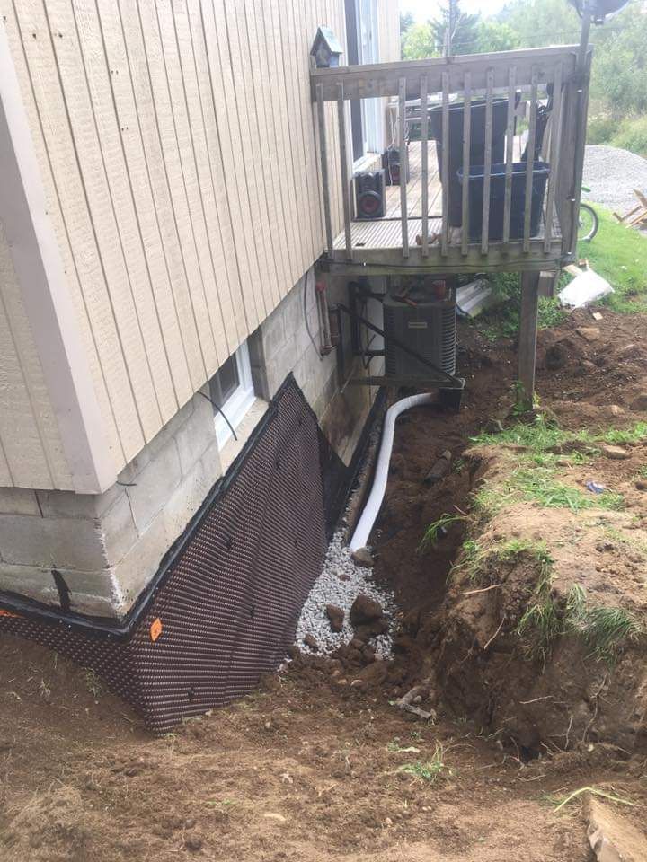A drainage system is being installed on the side of a house.