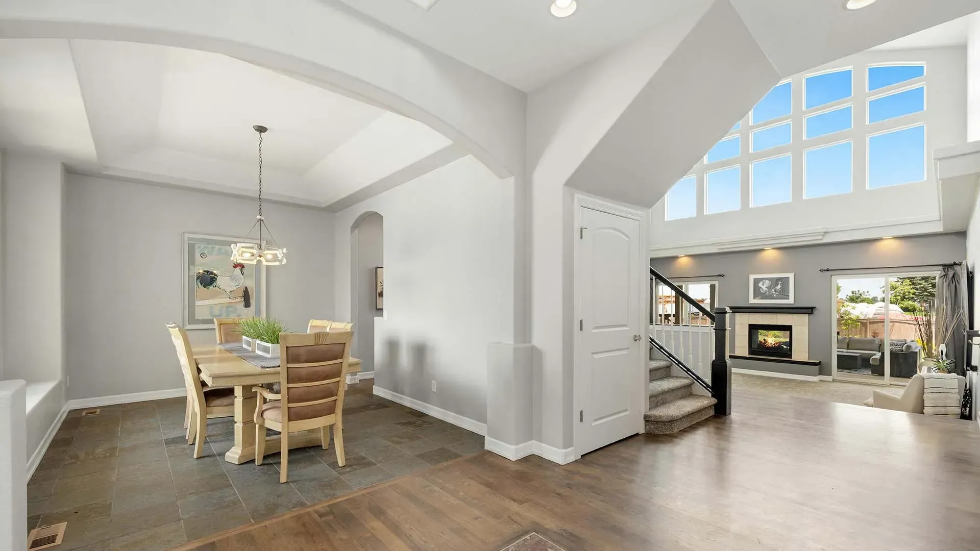 Bright open-plan dining and living room with white walls, wood floors, and large windows.