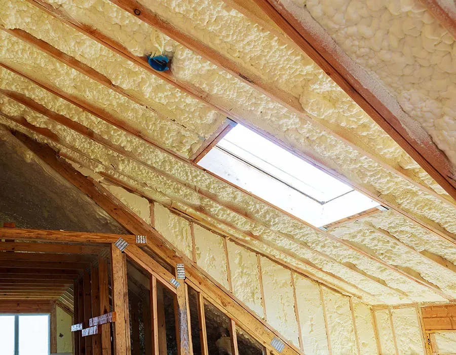 Insulated attic ceiling with skylight and exposed wooden framing in a partially finished room