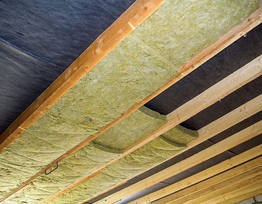Exposed ceiling framing with green insulation batts installed between wooden joists