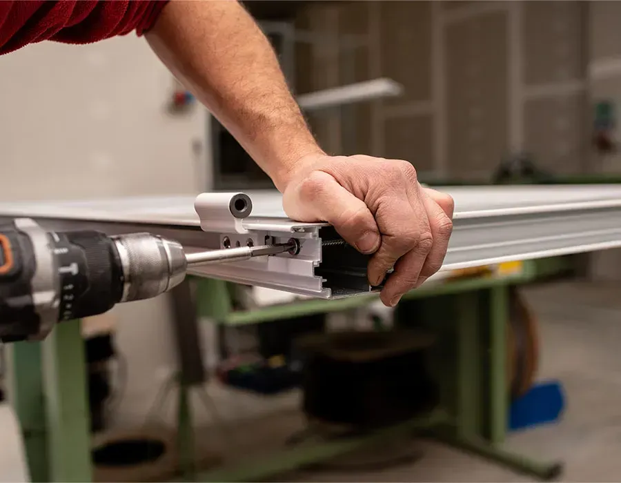 Hand drilling a metal rail with a clamp in a workshop