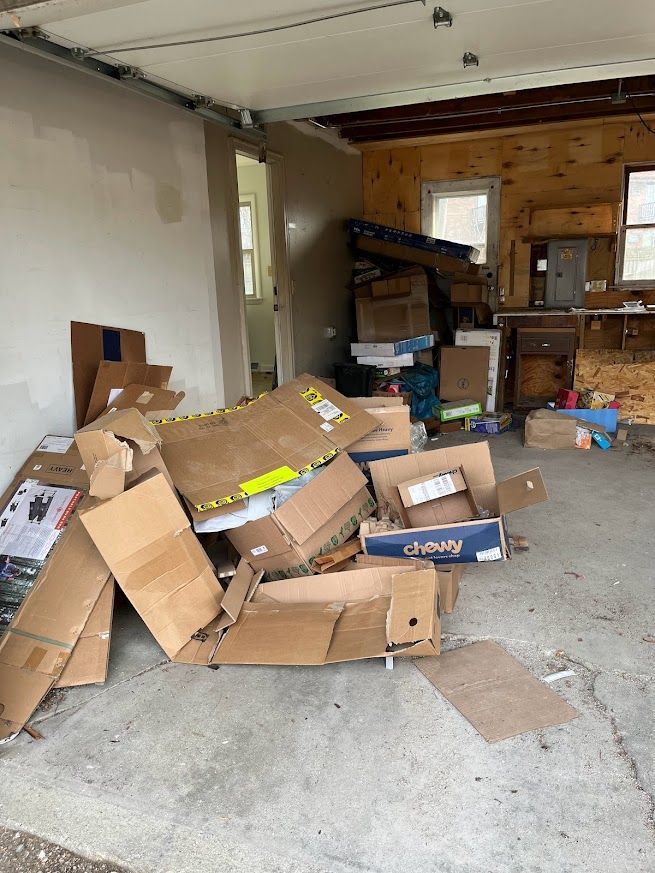 Garage interior with pile of cardboard boxes and other items; doorway visible.