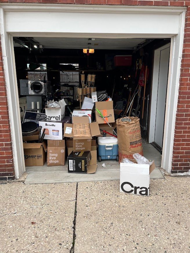 Open garage filled with cardboard boxes, appliances, and various items.