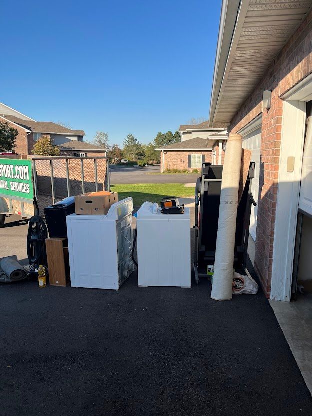 Appliances awaiting recycling: refrigerators, washing machine, and green container. Outdoor setting with fence.