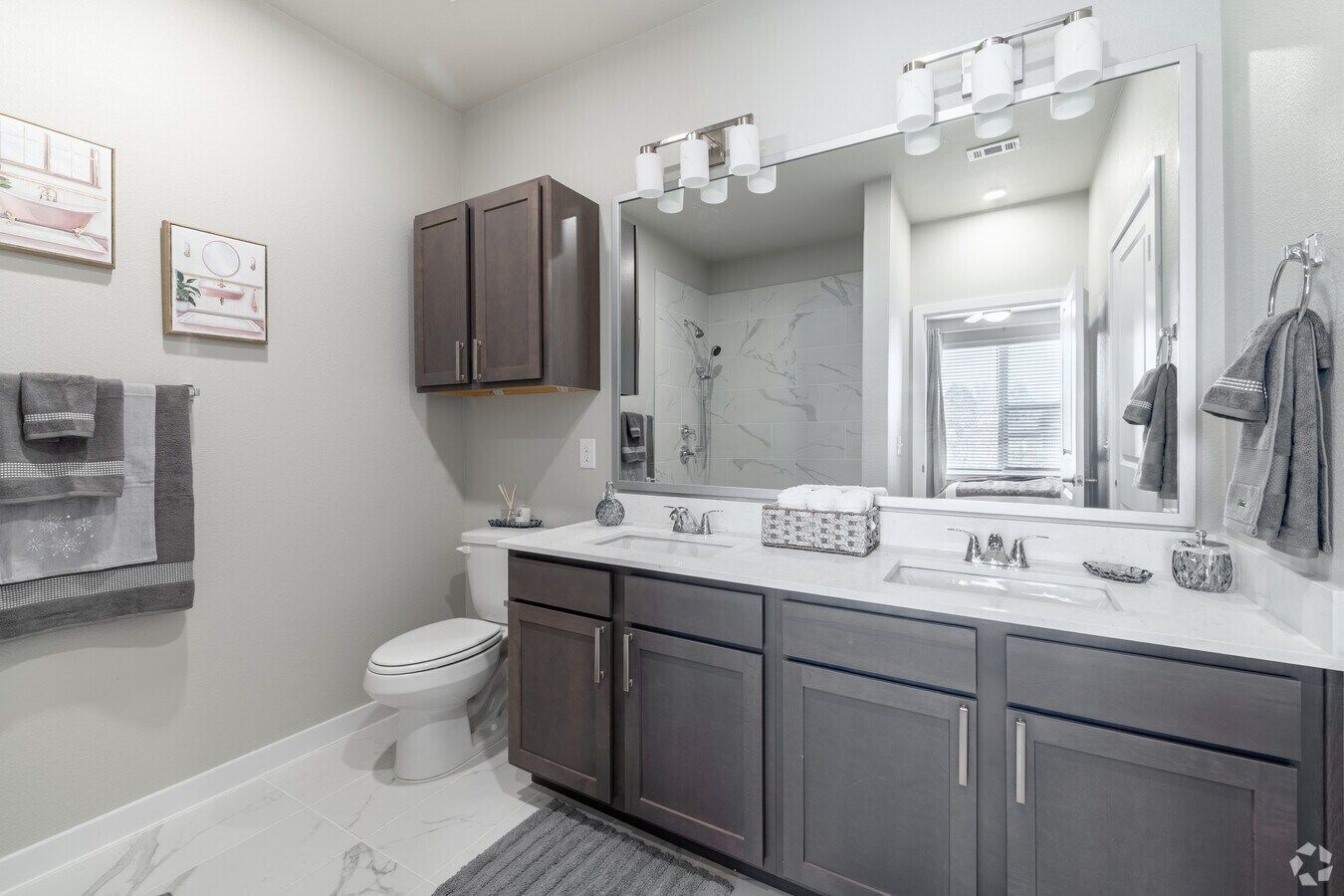 Urban Village at Rosehill apartment bathroom with a double vanity, gray cabinets, and an oversized mirror.