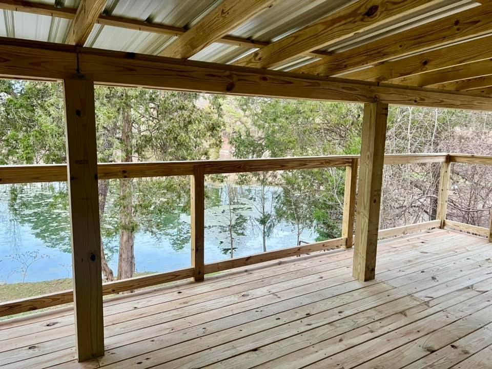 Covered wooden deck overlooking a calm lake and trees