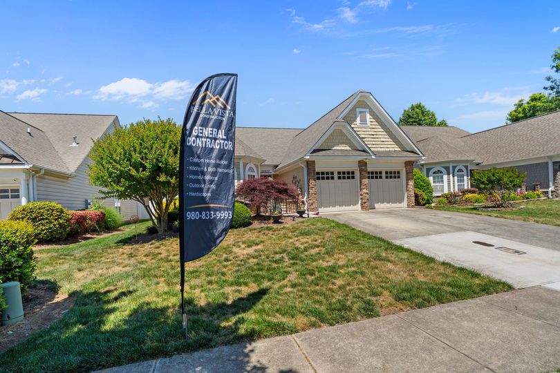 Suburban house with a driveway and a blue real estate flag in the front yard
