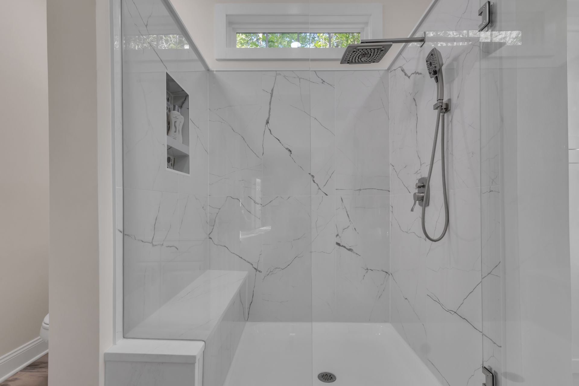 Modern white tiled walk-in shower with glass enclosure and handheld showerhead
