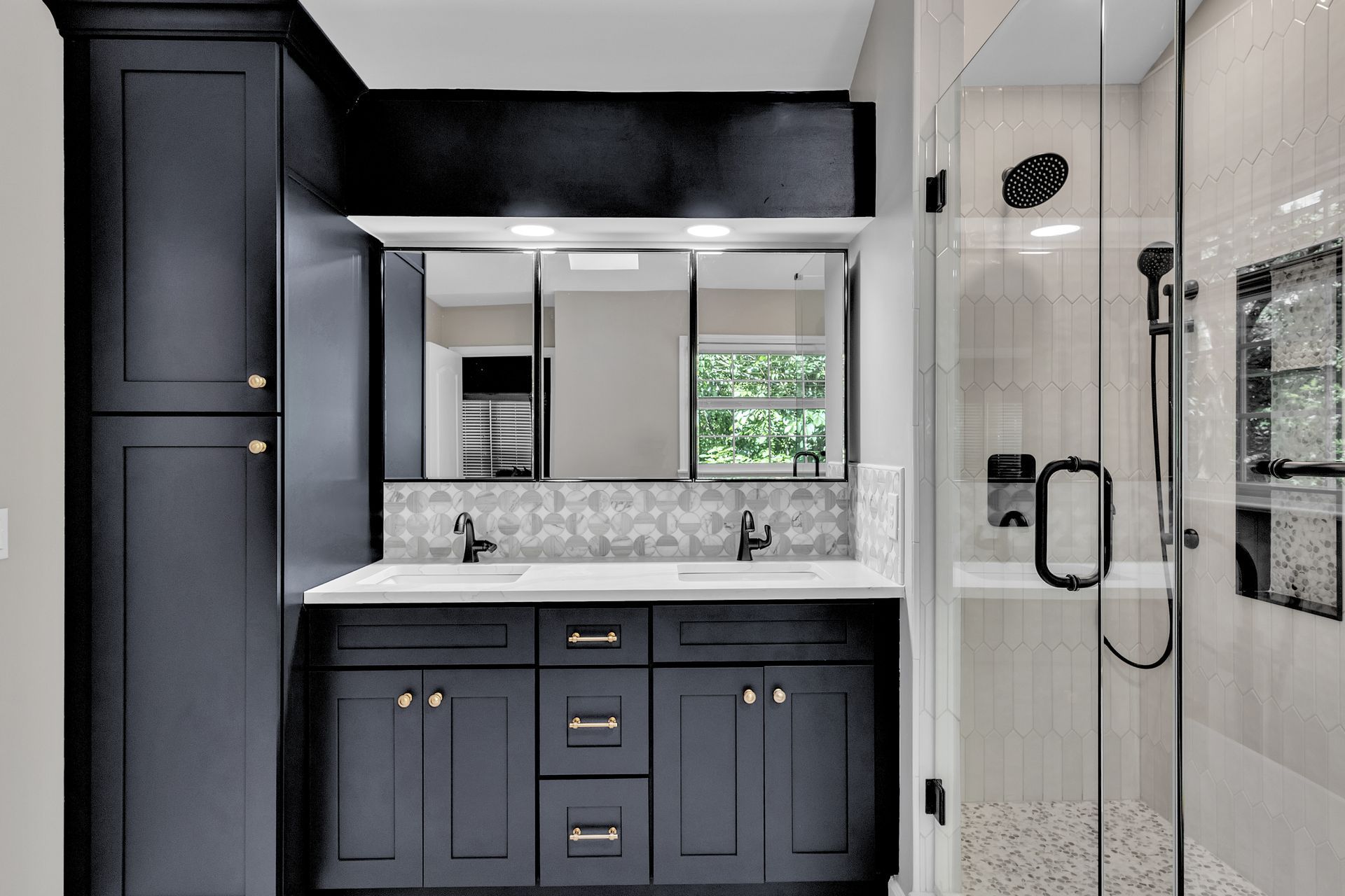 Modern bathroom vanity with dark cabinetry, marble countertop, mirror, and glass shower enclosure