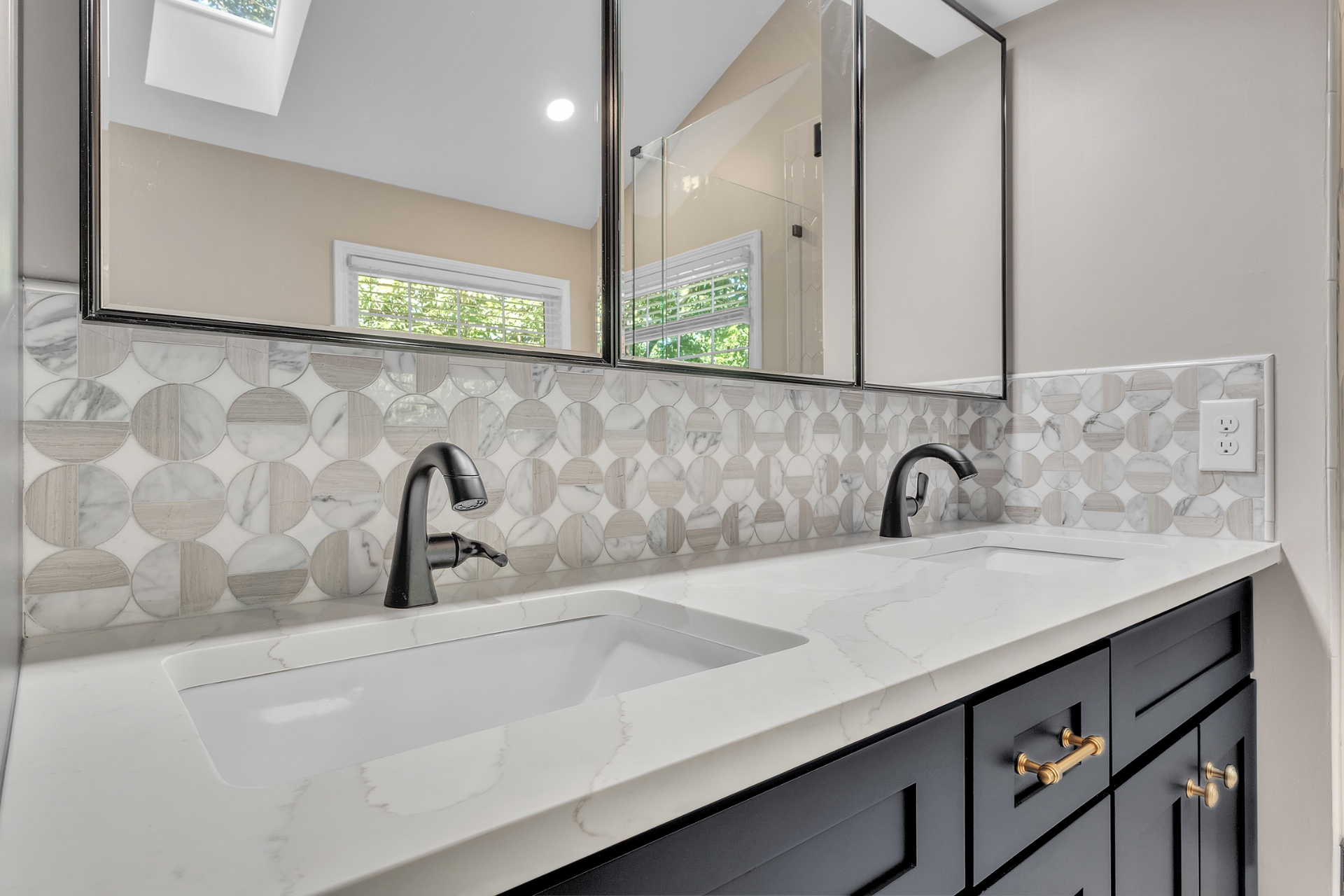 Modern double bathroom vanity with black faucets, white countertop, and geometric tile backsplash