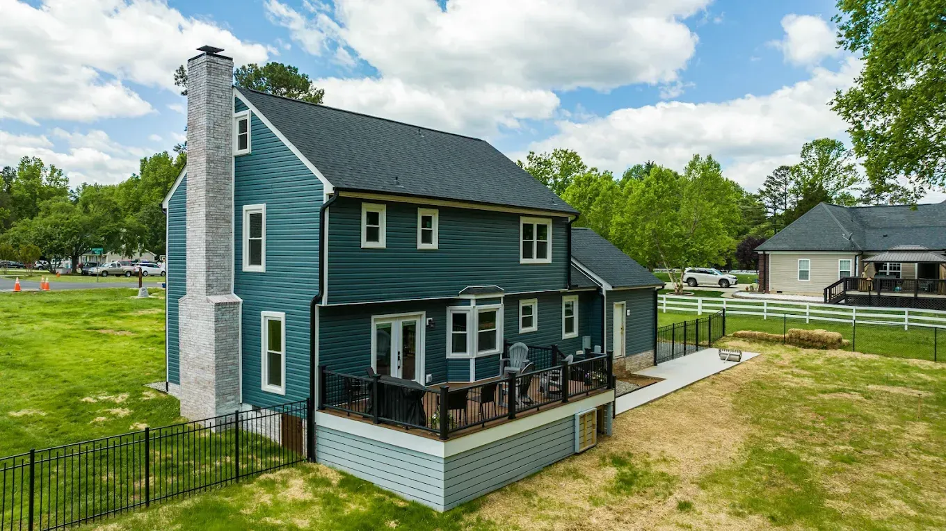 Two-story blue house with white trim and a covered front porch on a grassy lot.