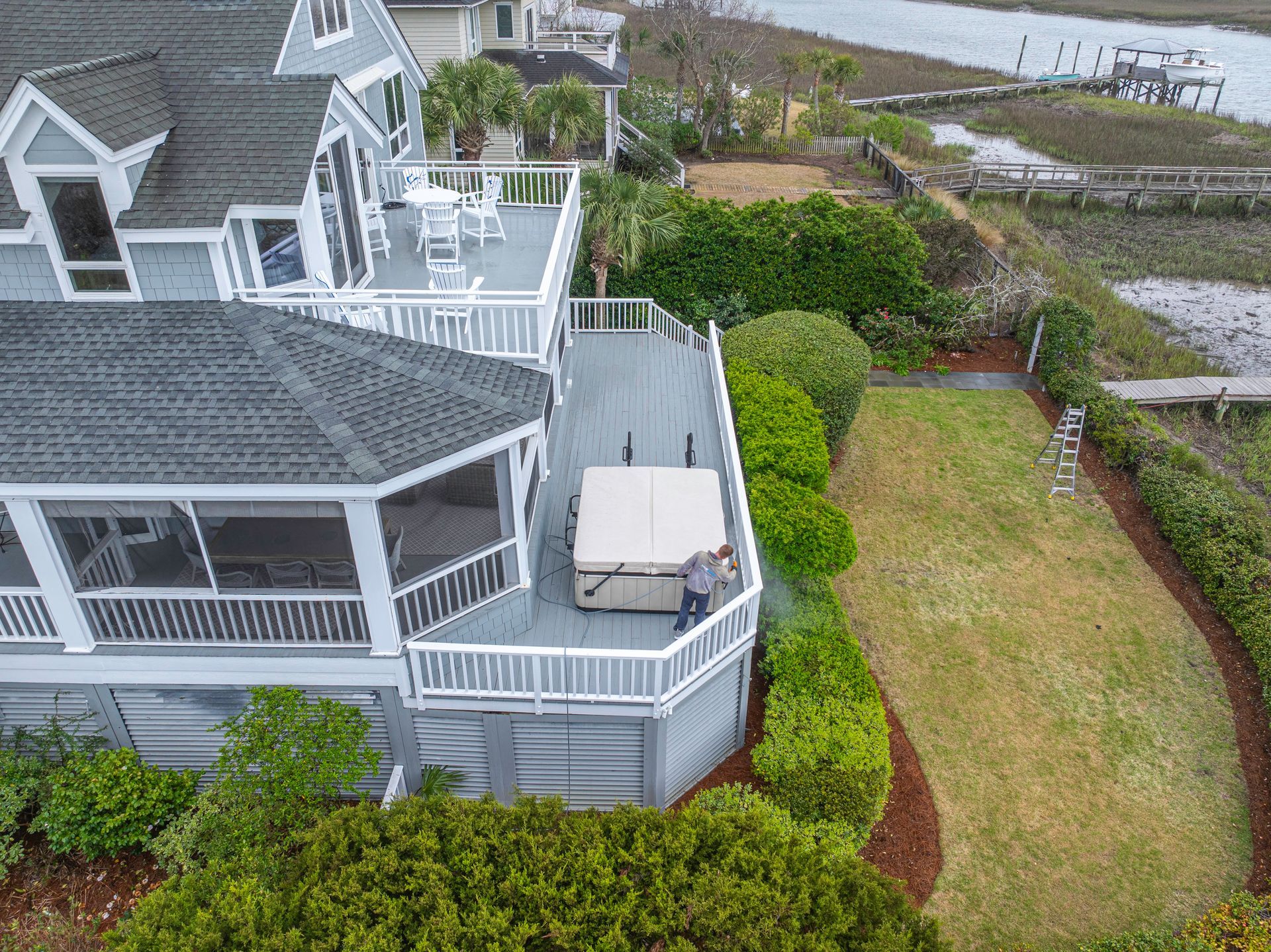 TrueWash technician soft washing the deck of a Sullivan's Island home overlooking the marsh