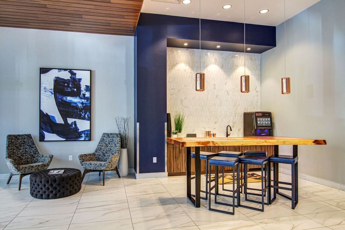 A living room with a table and chairs and a painting on the wall.