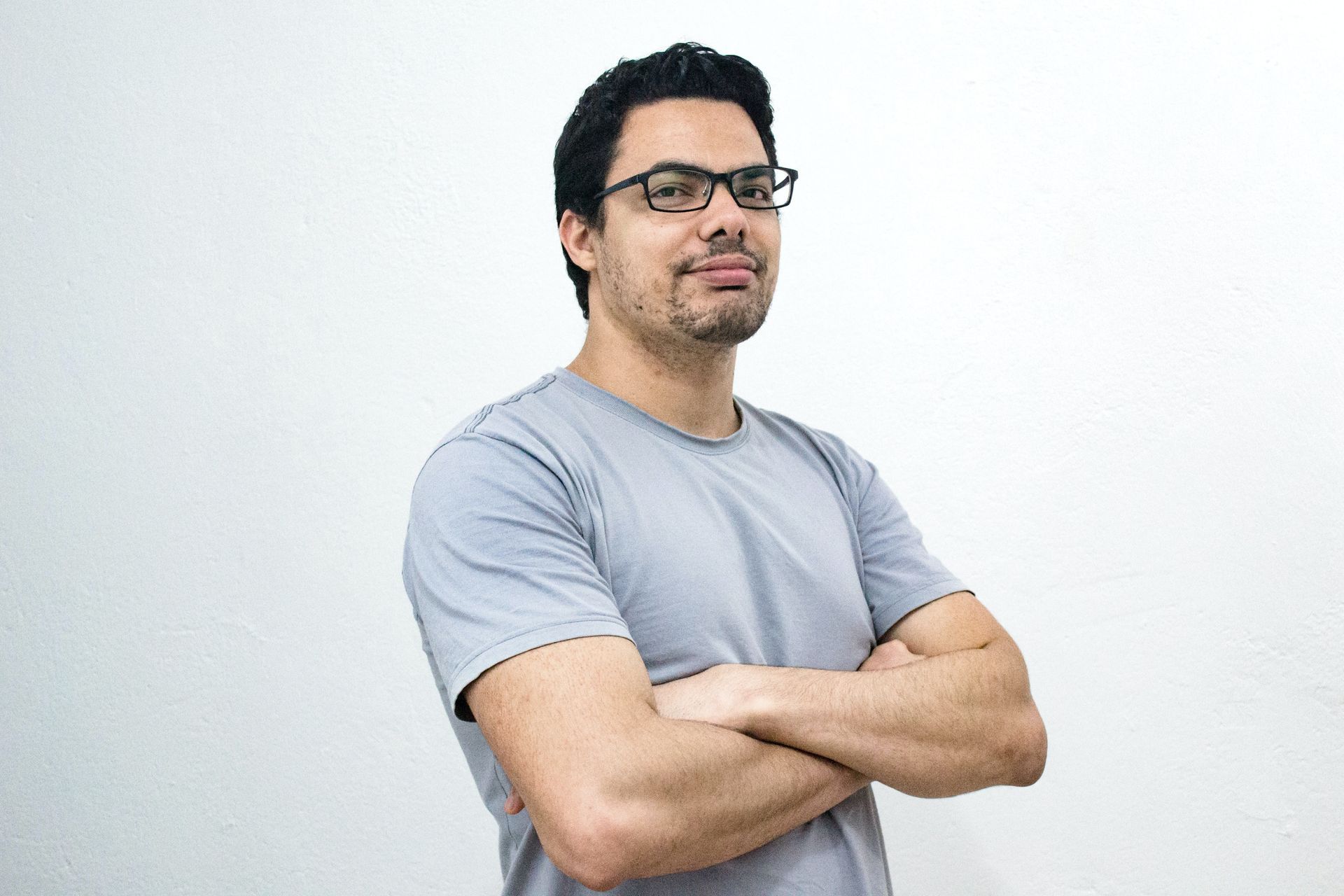 A satisfied male therapy client is standing with his arms crossed.