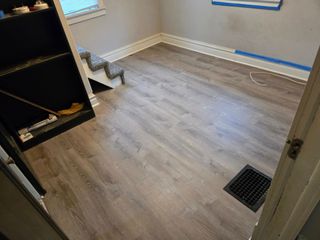 Room with new wood-look flooring; small staircase, built-in shelving, a vent, and a window.