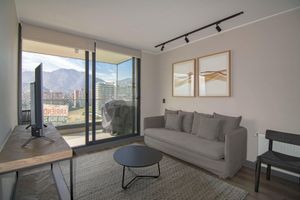 Living room with sofa, coffee table, and a large window overlooking a city and mountains.