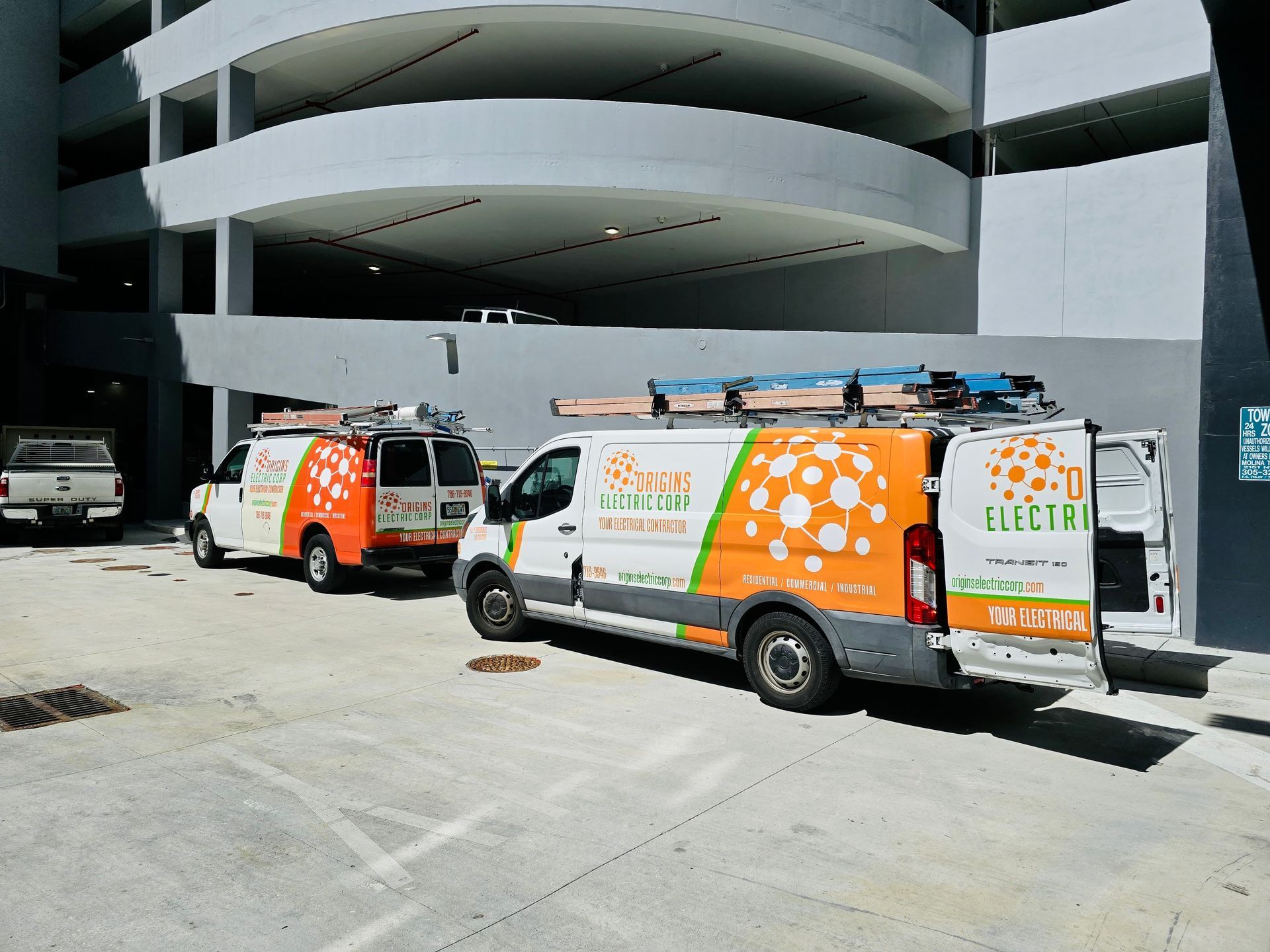 Two orange-and-white service vans parked outside a modern building entrance