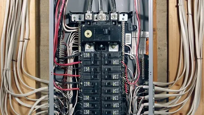Open electrical breaker panel with many wires and circuit breakers neatly arranged