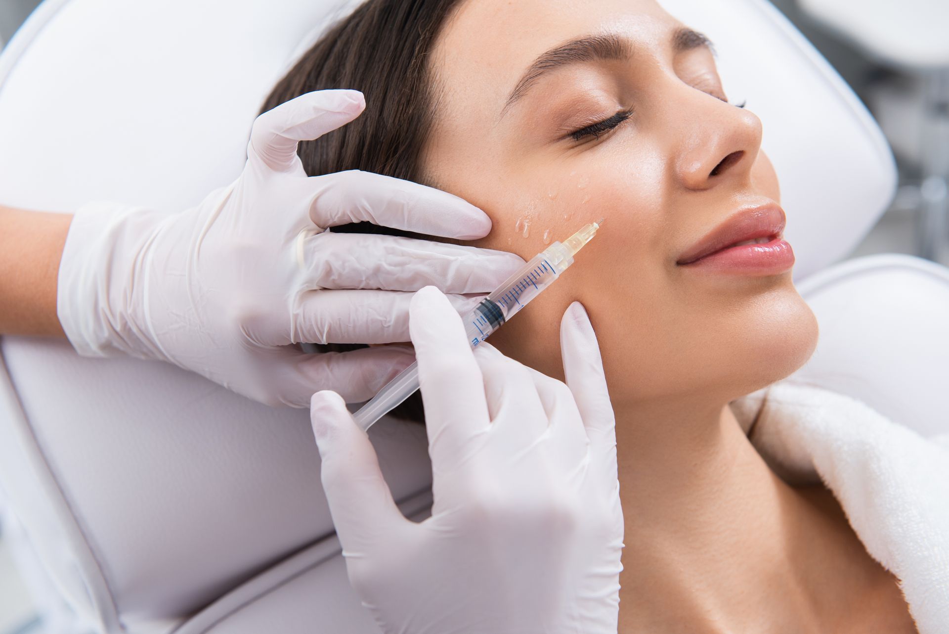 Stylized face outline with a syringe, suggesting cosmetic injection or skincare treatment logo