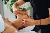 Line-art facial massage illustration with a hand on the neck and gold accent circles.