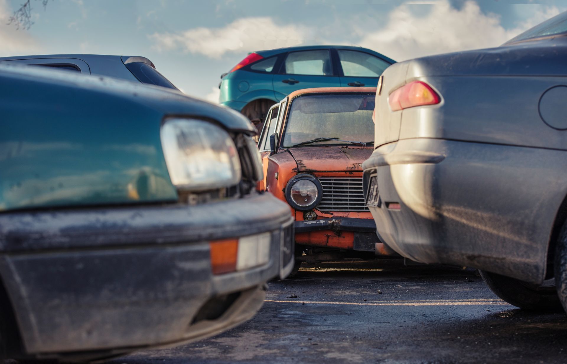 Older vehicles parked closely together in a crowded salvage yard.