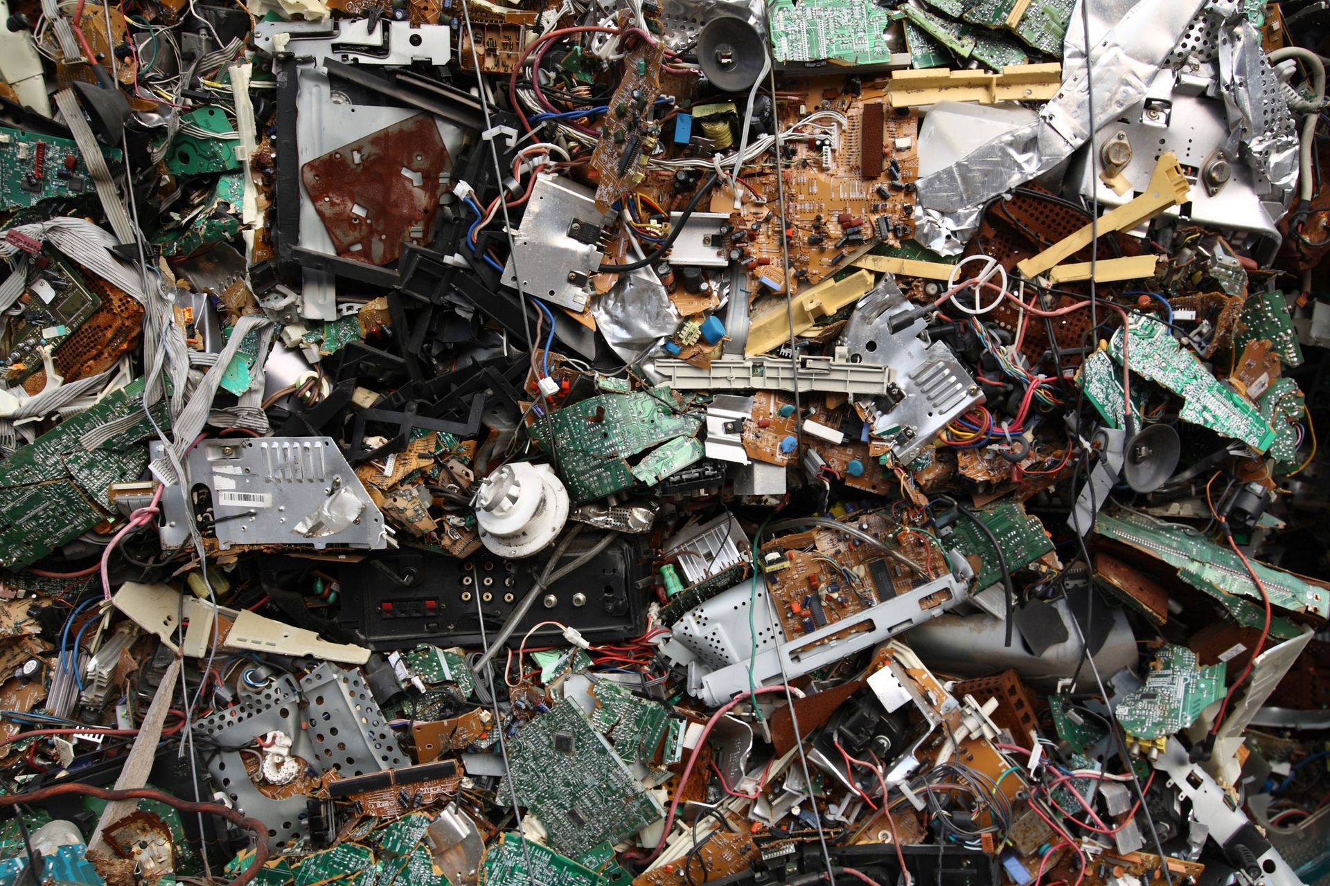 A dense pile of discarded electronic waste, including circuit boards, metal casings, and tangled wires.