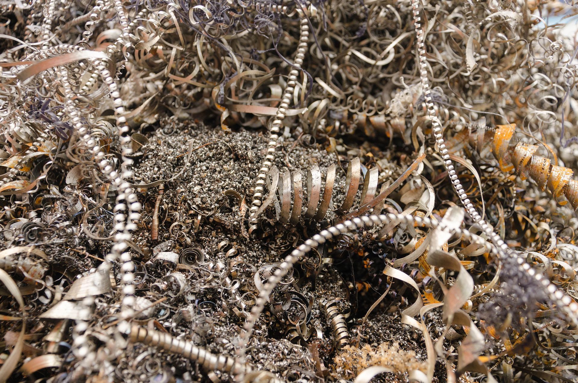 A close-up view of a pile of metallic industrial shavings and twisted metal chips scattered in a workshop.