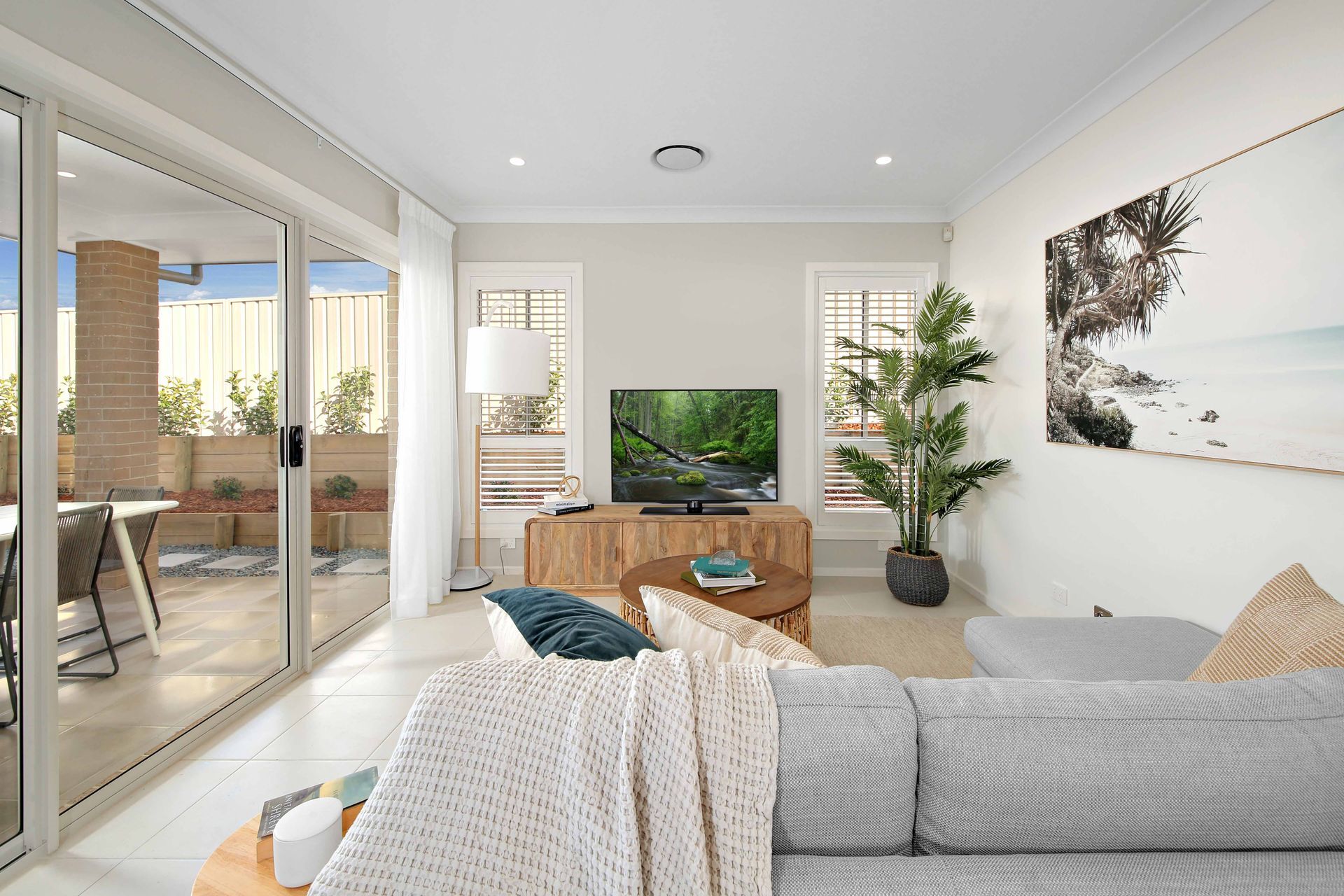 Grove 24 - A living room with a couch, table, television and sliding glass doors.