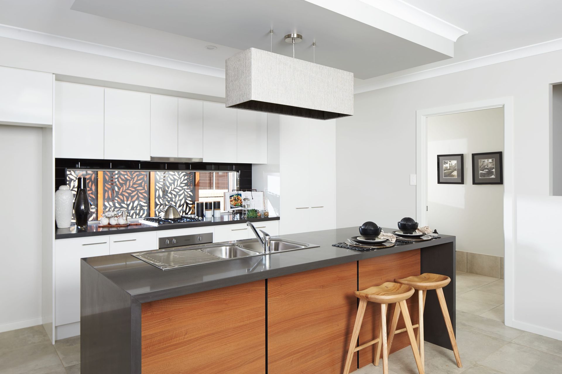 Harmony 23 home design - A kitchen with white cabinets and a large island with stools.