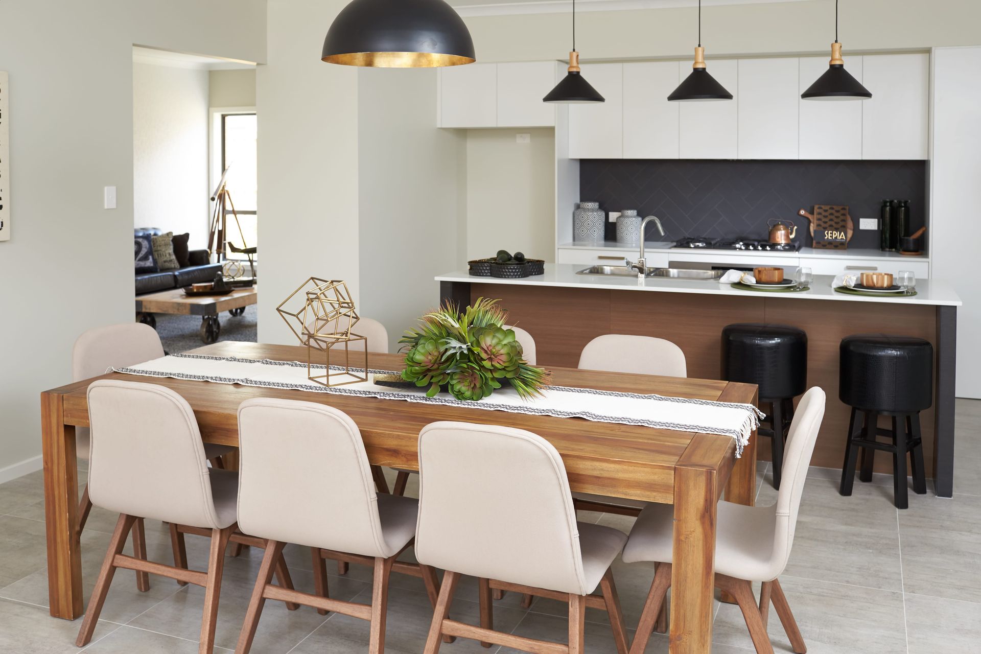 Harmony 26 home design - A dining room with a wooden table and chairs and a kitchen in the background.