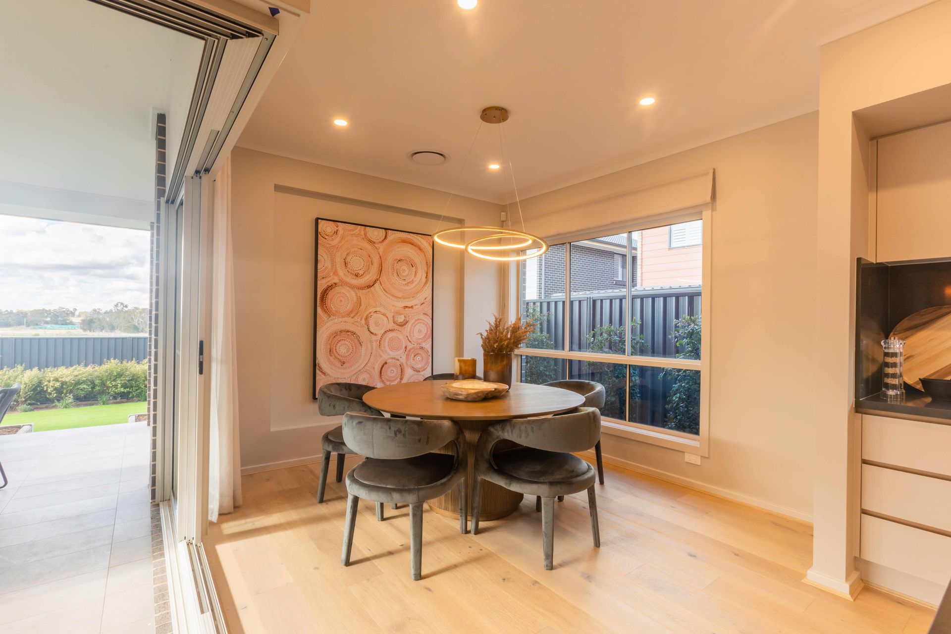 Riviera 25 home design - A dining room with a round table and chairs and a large window.