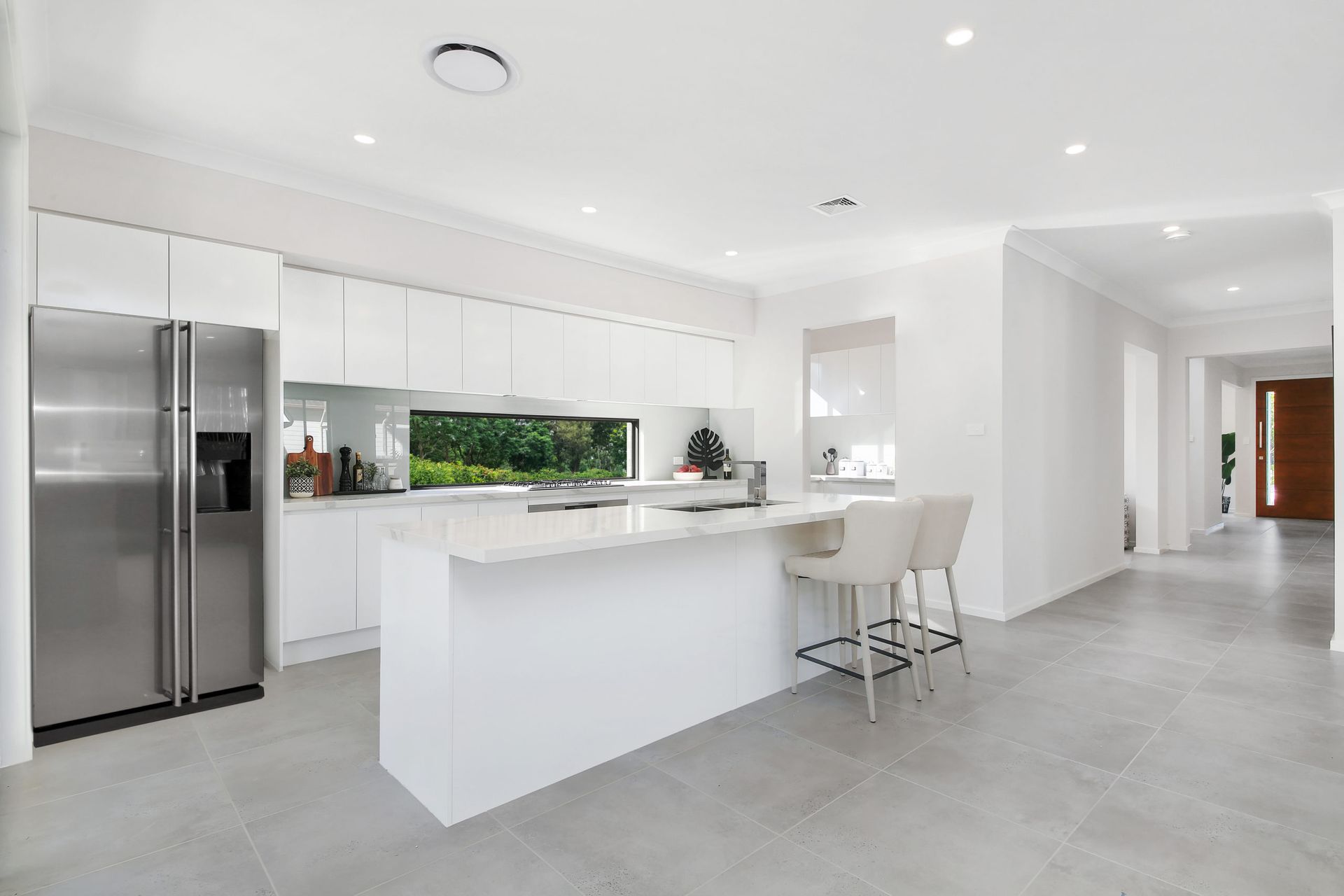 Savoy 38 home design - A kitchen with white cabinets, stainless steel appliances, and a large island.