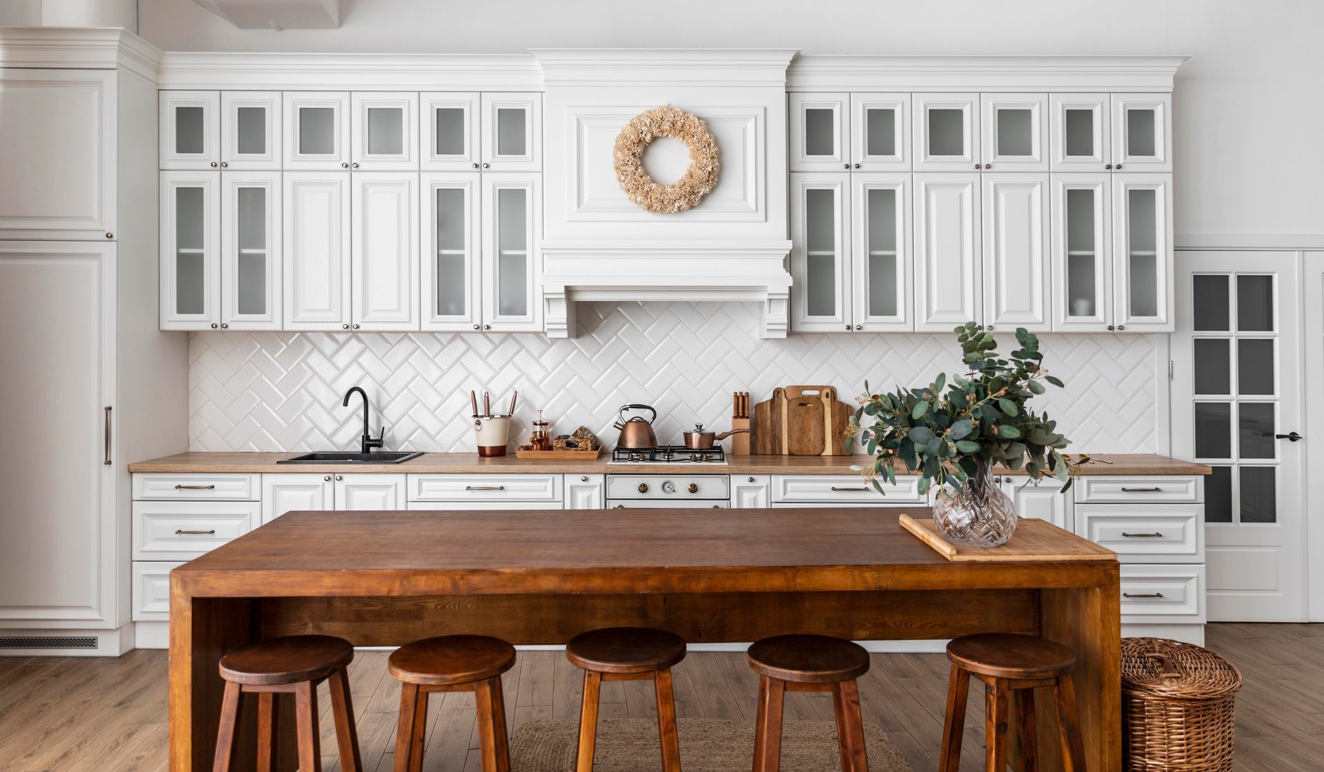 Hillside 24 home design of a kitchen with white cabinets, a wooden table and stools.