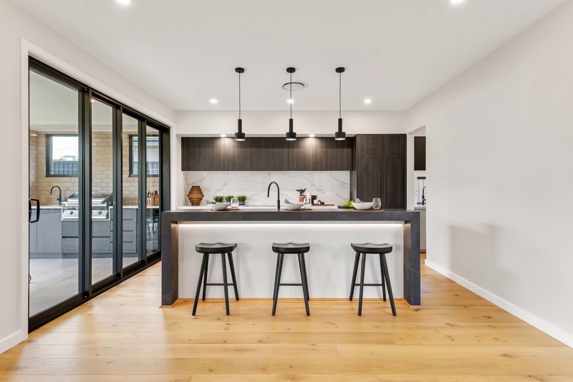 Vineyard 32 home design - A kitchen with a large island and three stools.