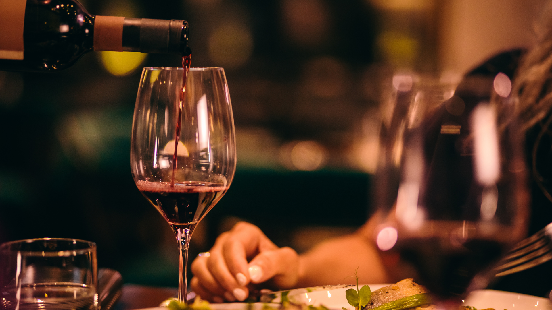 a person is pouring wine into a glass at a restaurant .