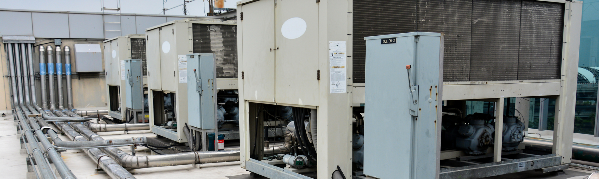 HVAC rooftop units and ductwork on a flat industrial roof, with open service panels