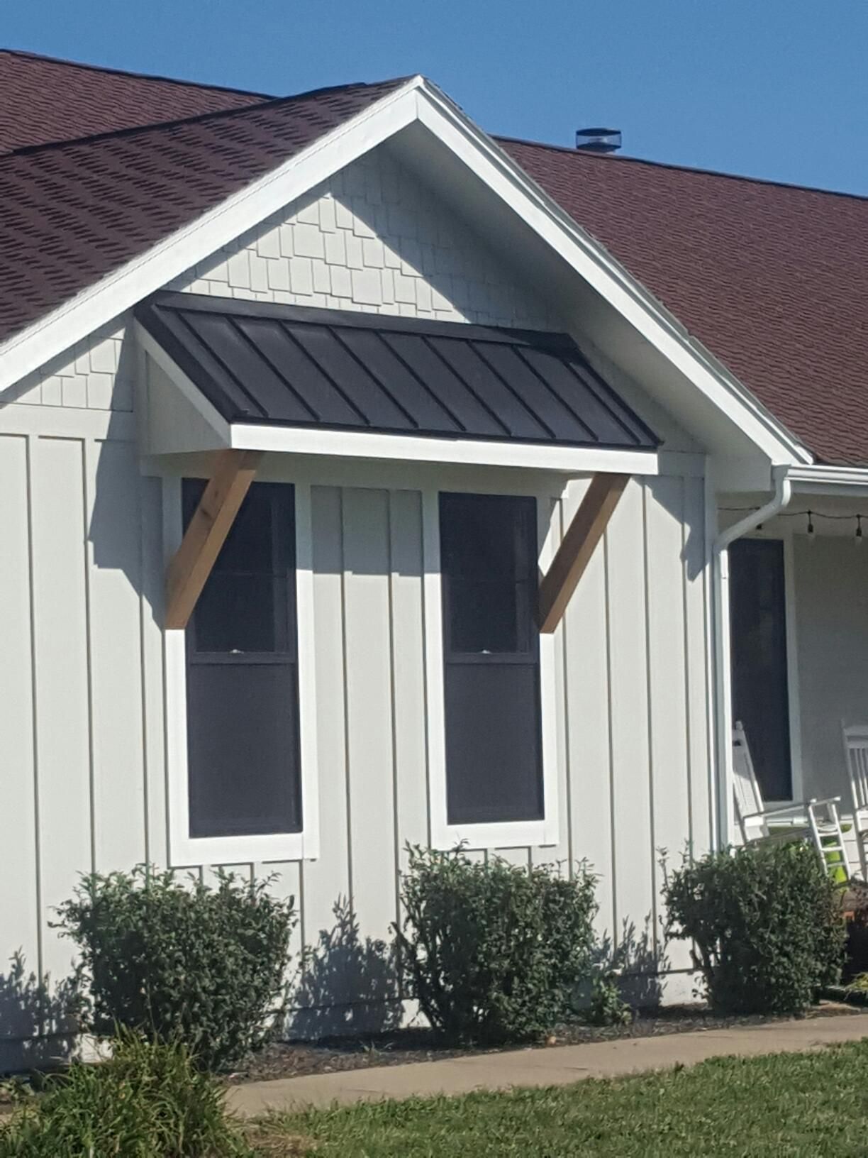 A white house with a black roof and a porch