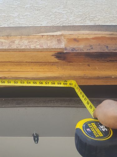 A person is measuring a piece of wood with a tape measure.