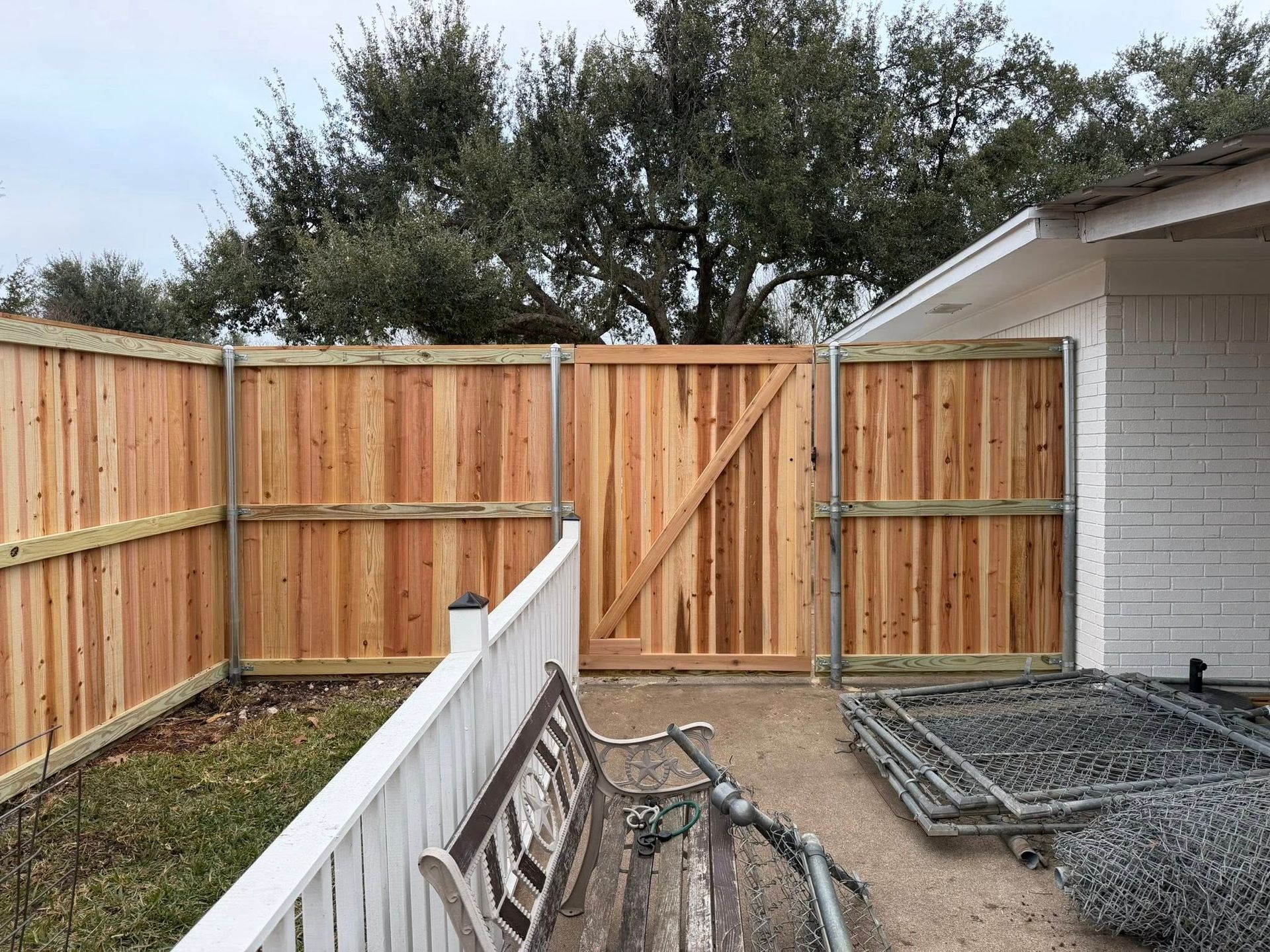 Backyard with new wooden fence, gate, and white house wall beside a gravel area