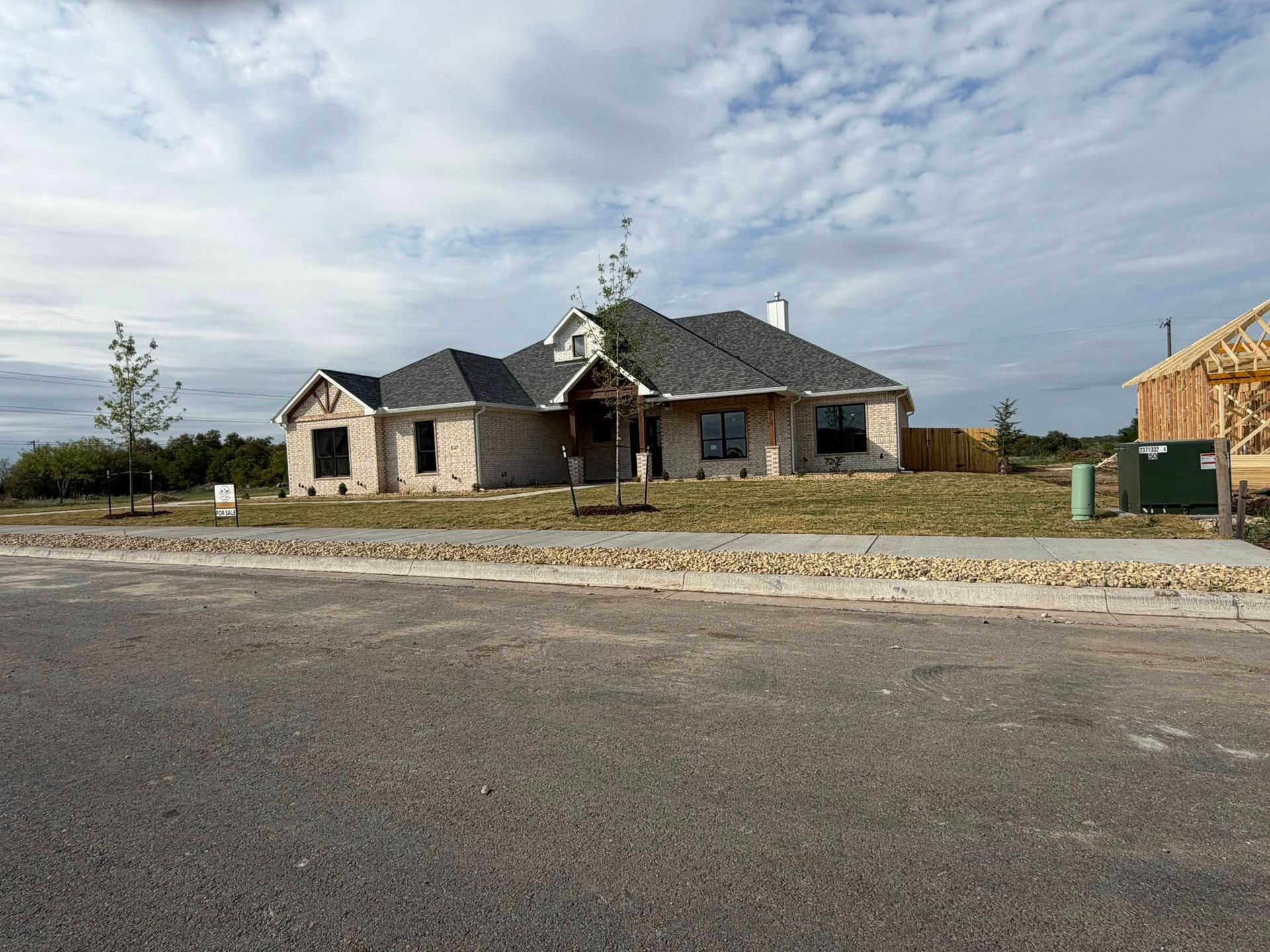 New house under construction beside a quiet road under a cloudy sky