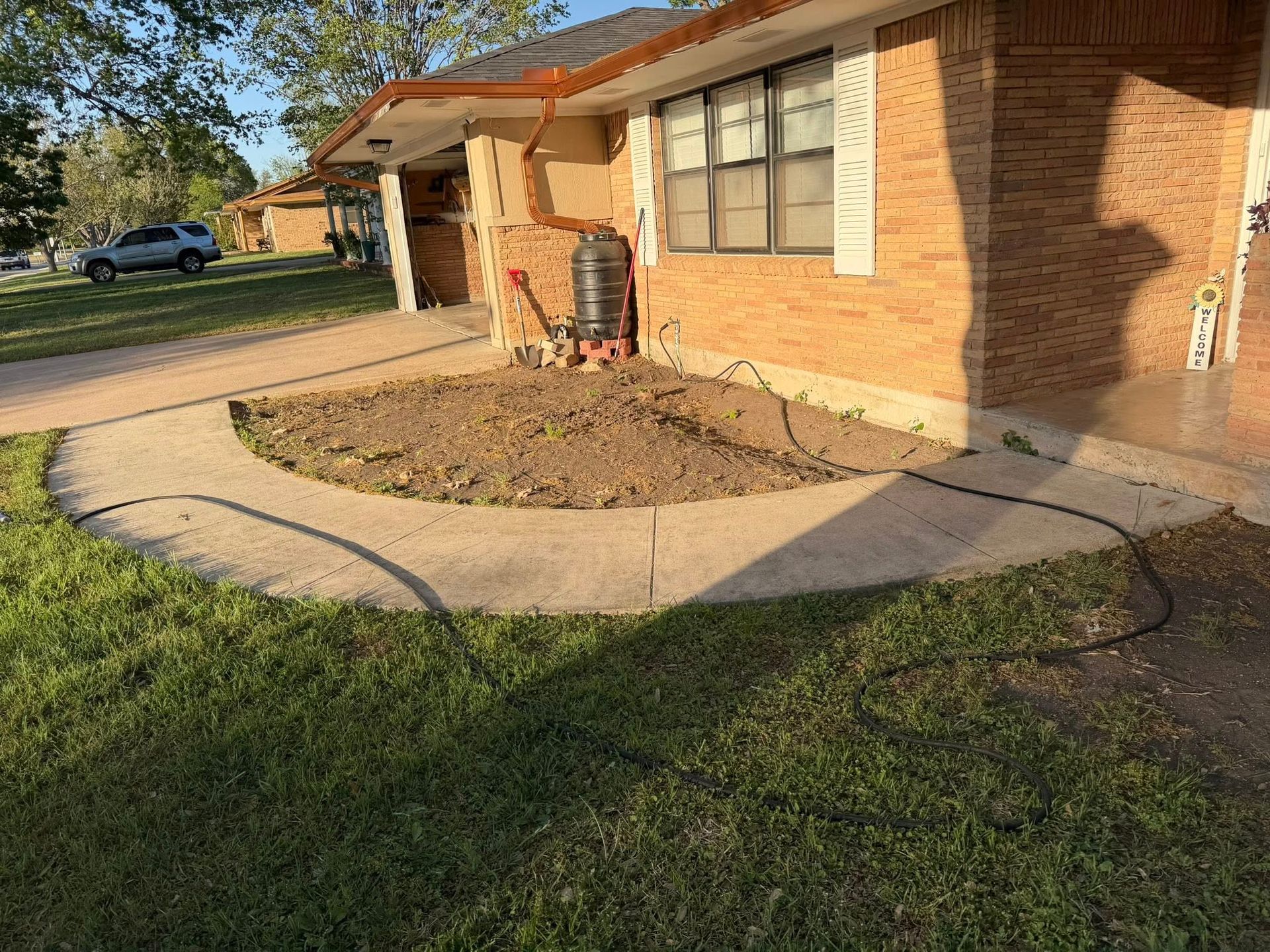 Brick house with a small front porch, curved walkway, and a young landscaped garden bed