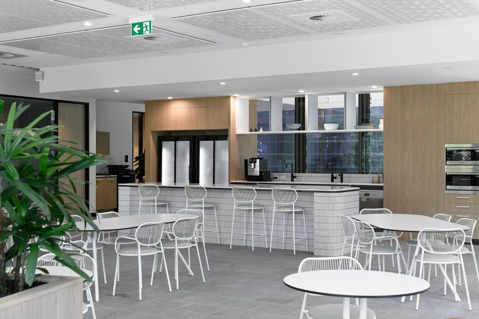 A Room with Tables and Chairs and A Green Exit Sign on The Ceiling — Thats Tops by Design in Taminda, NSW