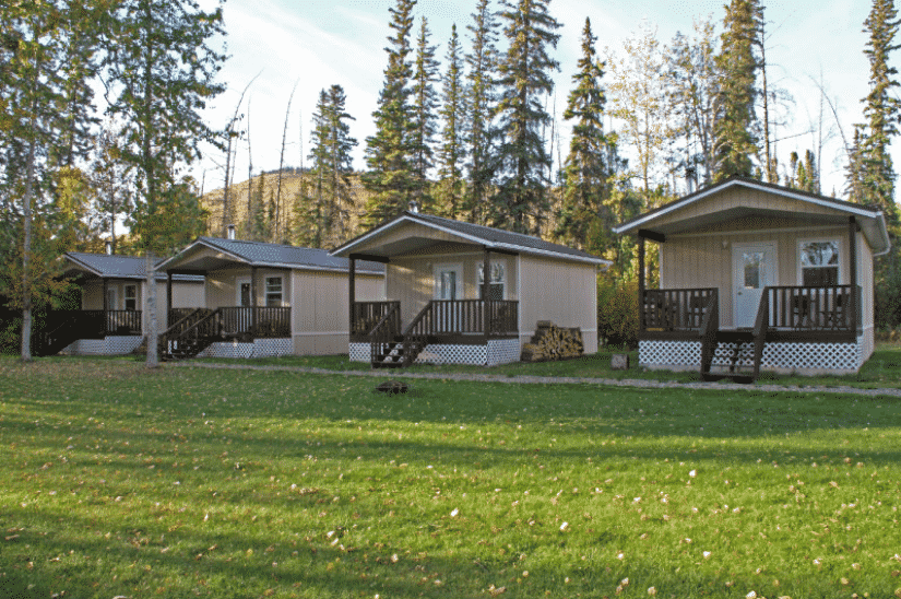 A row of small houses with porches are sitting on top of a lush green field.